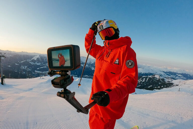 A lifestyle image of a man using the An angled shot of the GoPro HERO10 Black action camera in a snowy landscape.