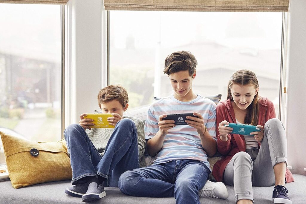 Three siblings playing their Nintendo Switch Lite consoles on a couch.